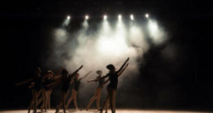 Ballet class on the stage of the theater with light and smoke. Children are engaged in classical exercise on stage.