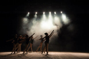 Ballet class on the stage of the theater with light and smoke. Children are engaged in classical exercise on stage.