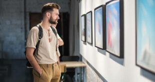 Young man in modern art exhibition gallery hall contemplating artwork. Abstract painting