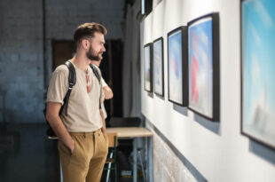 Young man in modern art exhibition gallery hall contemplating artwork. Abstract painting